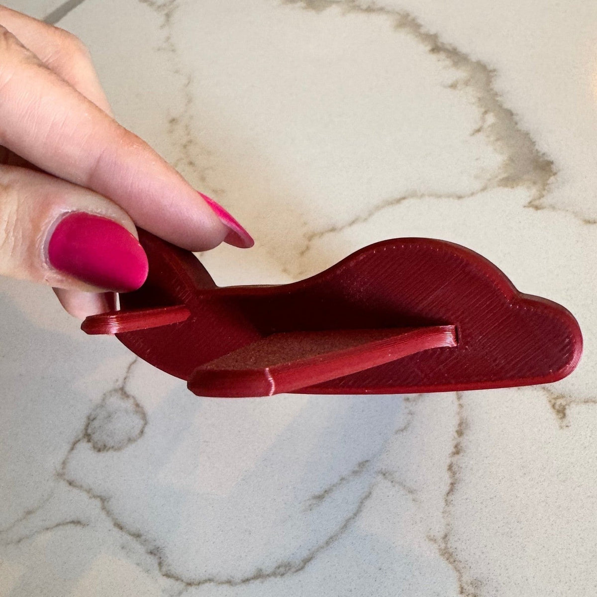 Avião de decoração infantil vermelho da Minha loja, feito em impressão 3D, segurado por uma mão.