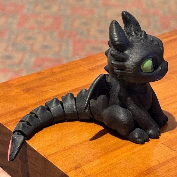 Boneco articulado Banguela Minha loja em impressão 3D preto com olhos verdes e cauda móvel sobre mesa de madeira