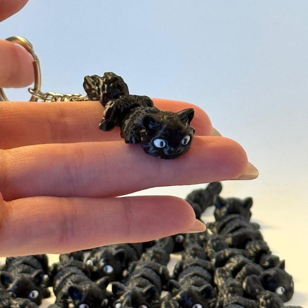 Chaveiro articulado de gato preto impresso em 3D da Minha loja, segurado na mão com detalhes realistas.